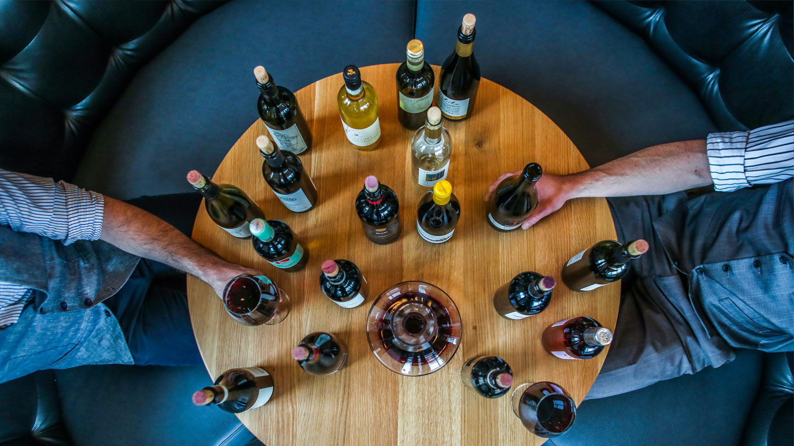 An aerial view of wine bottles on a wooden table.