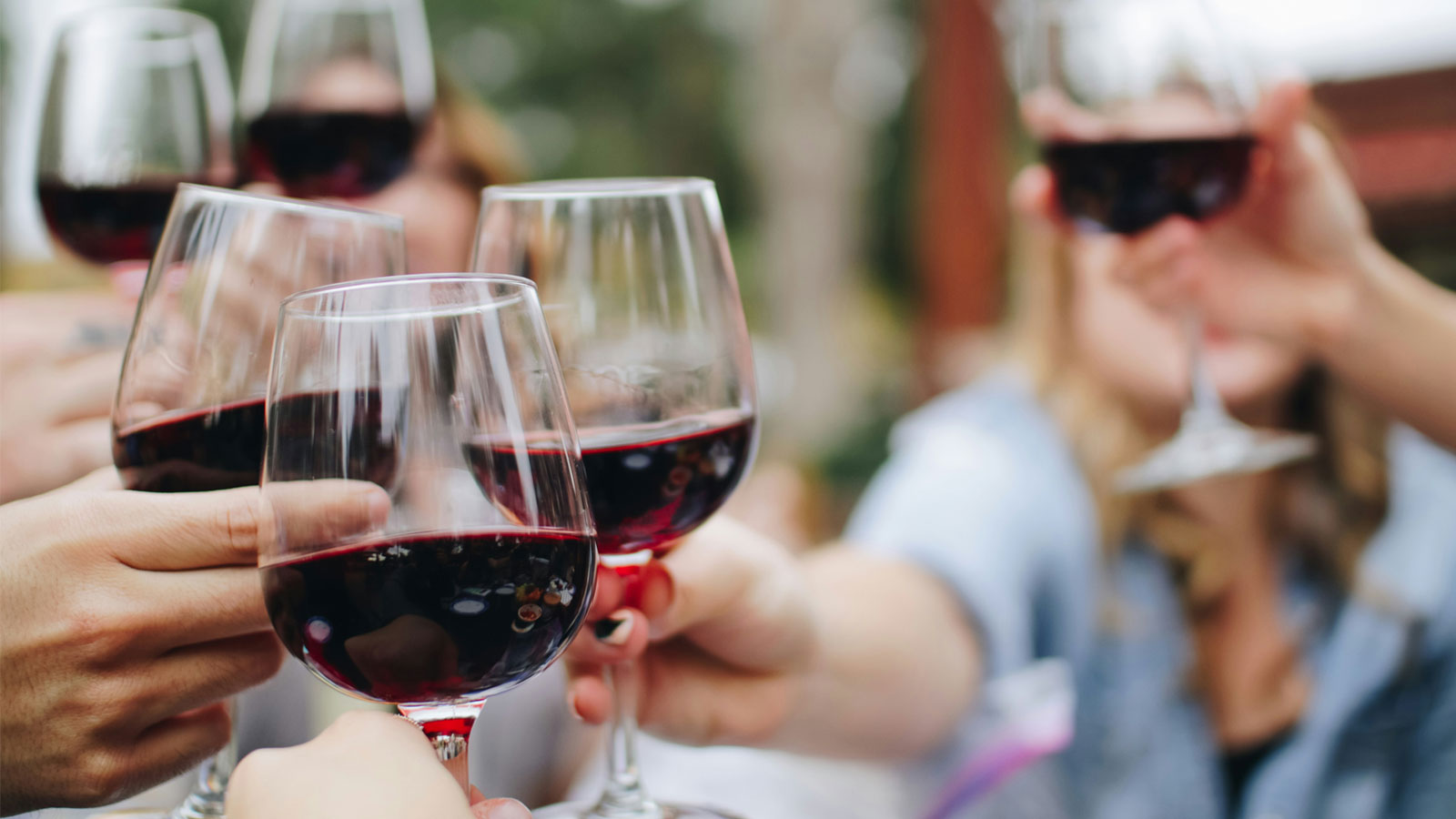 Close of hands clinking red wine glasses