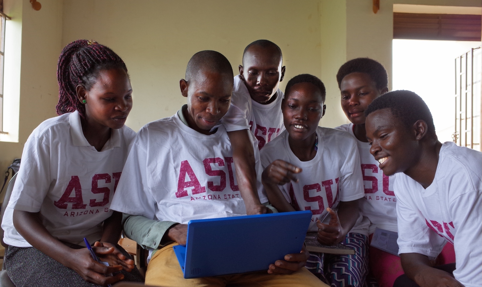 Six children looking into a laptop