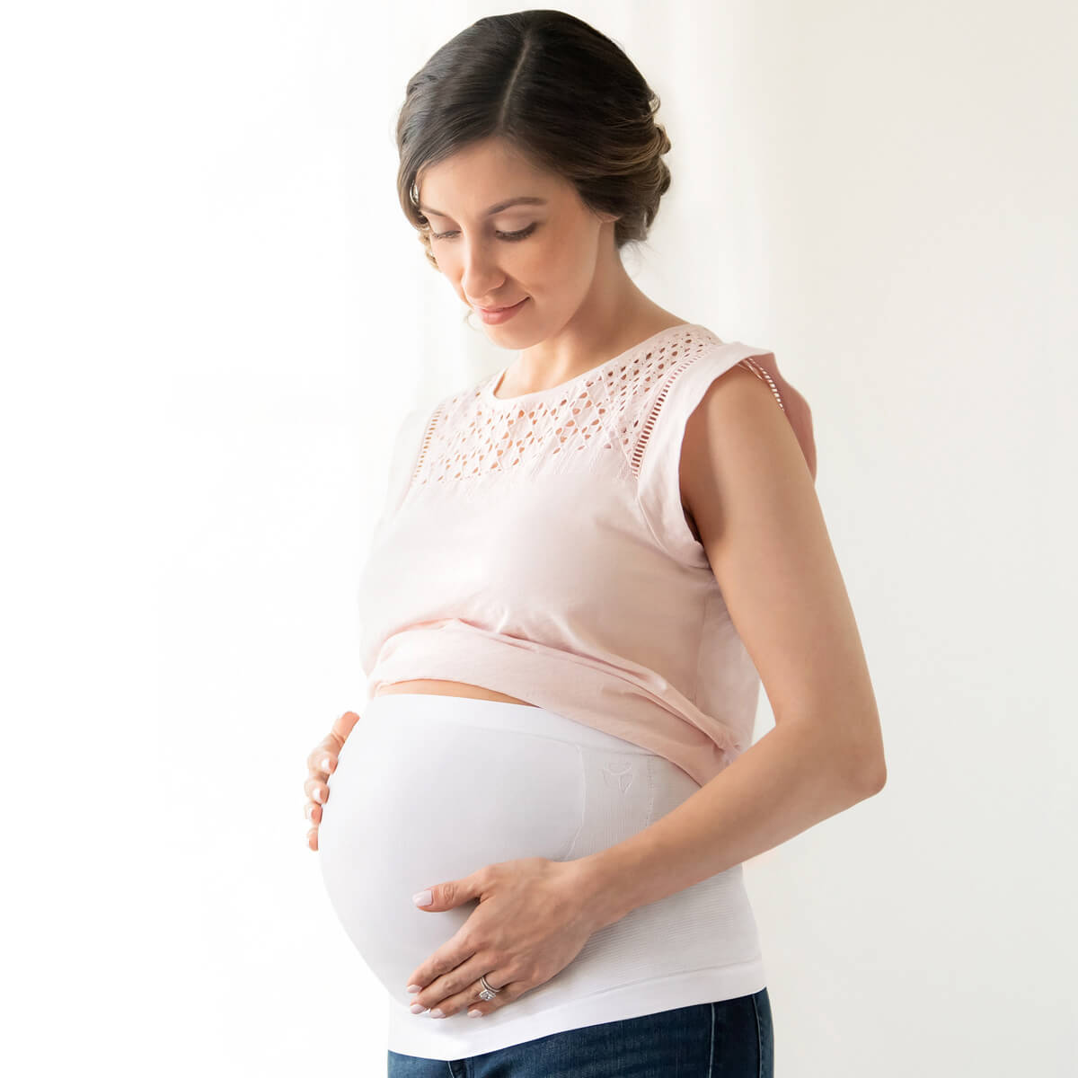 Woman with her hands on her baby bump, smiling