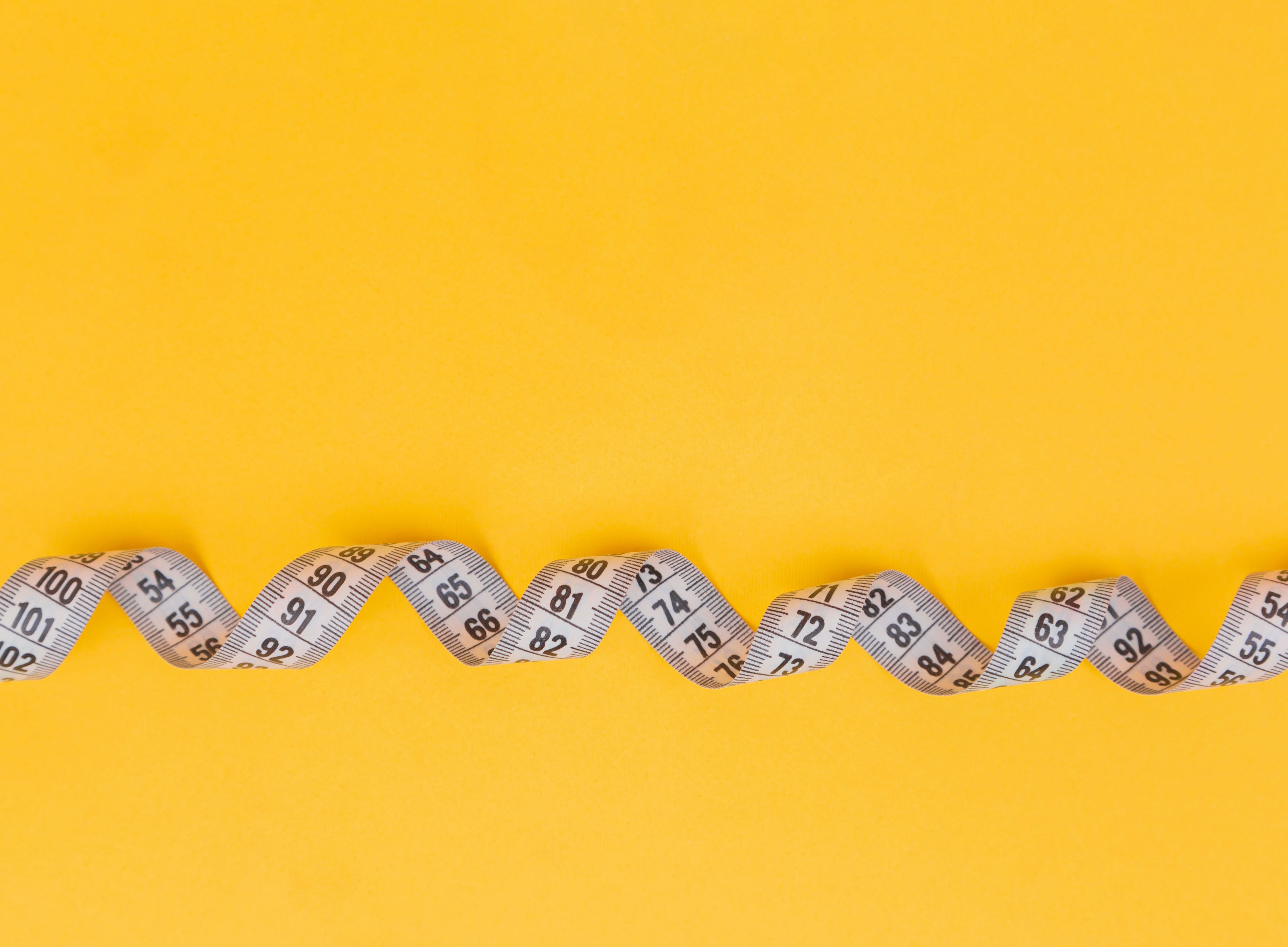 Sewing tape laying on a bright yellow background.