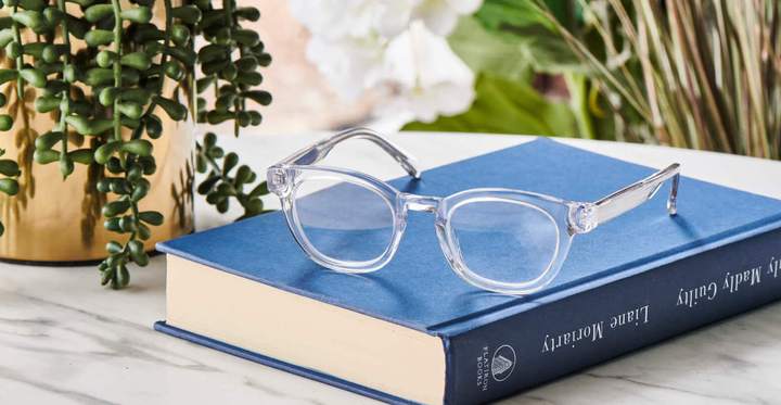 clear framed glasses sitting on top of book.