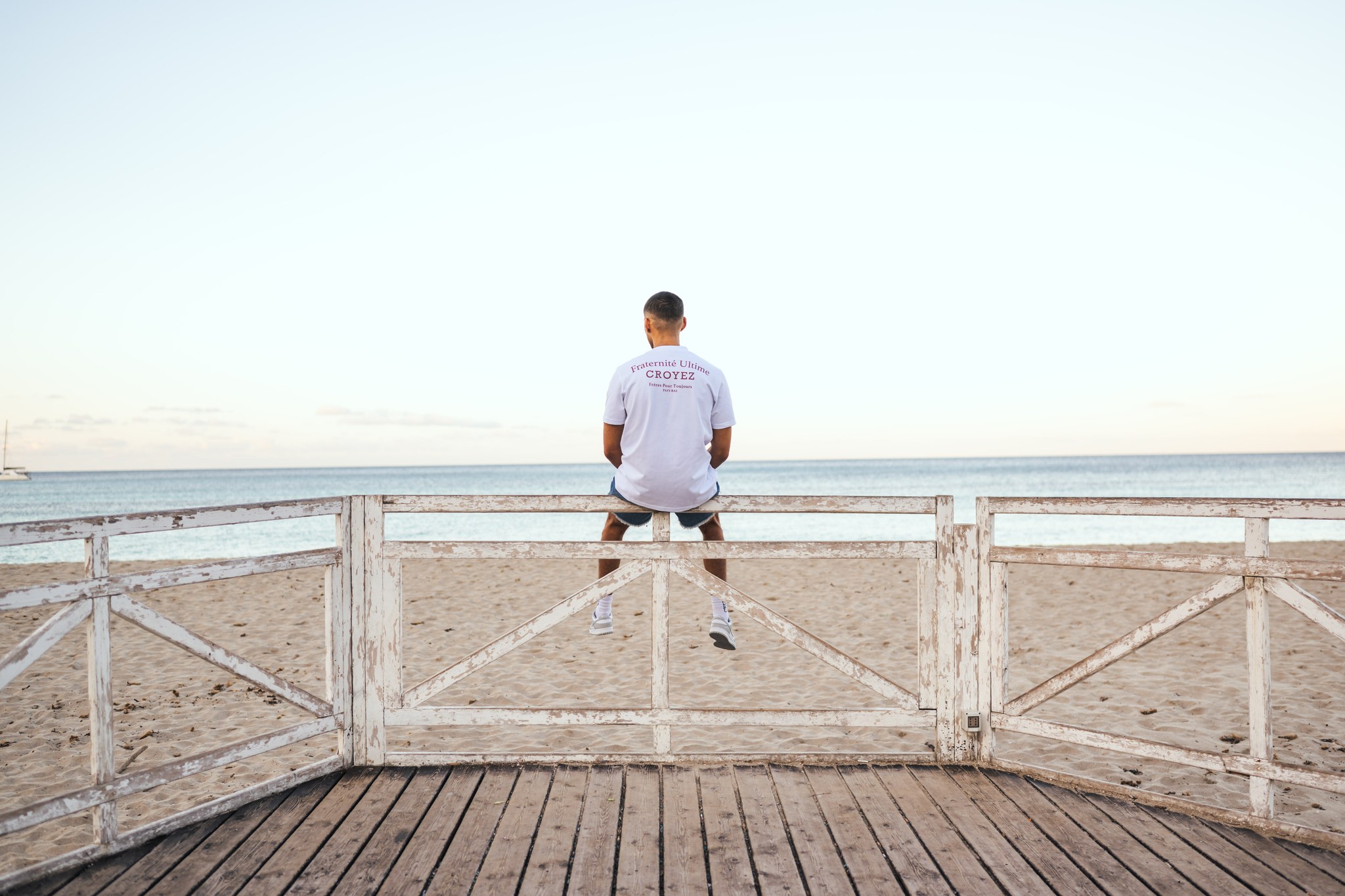 Man sitting in a fence looking at the sea