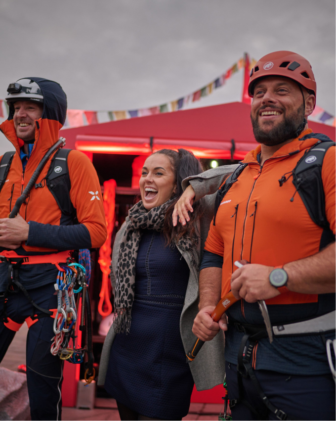 Two men and one woman wearing climbing gear and smiling