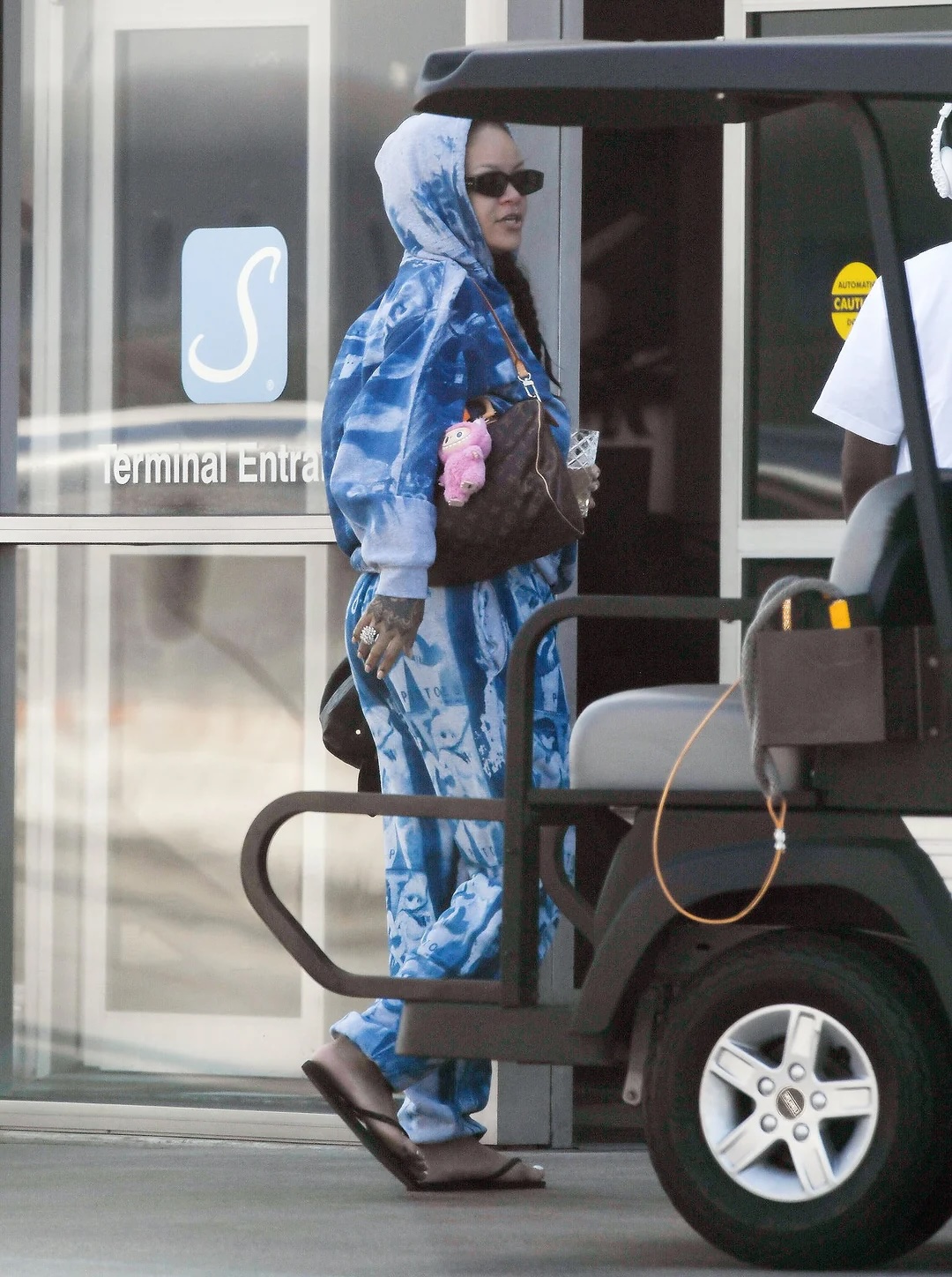 Woman in blue hoodie with plush keychain on brown handbag